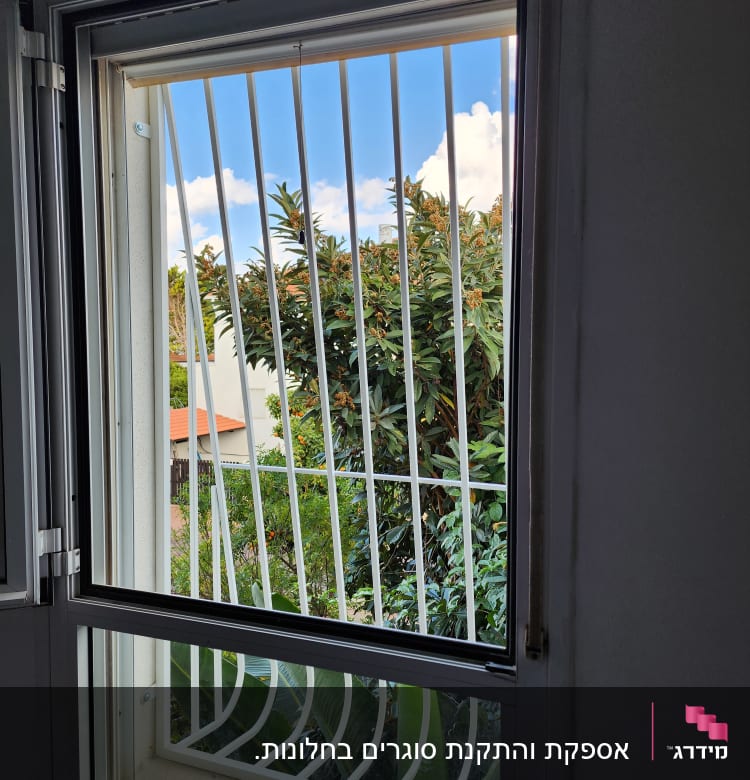 חלון עם סורגים לבנים ונוף חיצוני